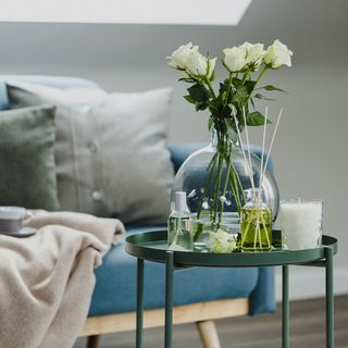 candles and diffuser on table with blue sofa