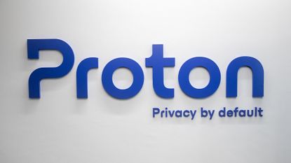 Proton logo and branding, including 'Privacy by Default' term, pictured in blue lettering on a white wall.