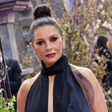 a woman with dark hair styled in a high bun posing for a camera at a television premiere event