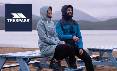 Trespass logo placed over an image of two people in rain coats with a lake behind them 