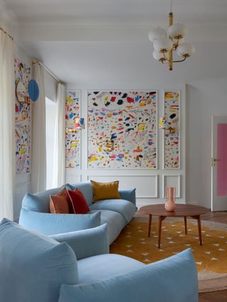 A living room with white walls with panelling filled in with colorful patterned wallpaper