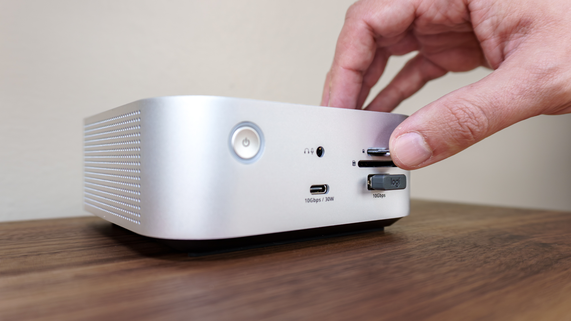 A person inserting a microSD card into a card reader on the front of the Satechi Thunderbolt 5 CubeDock on a desk