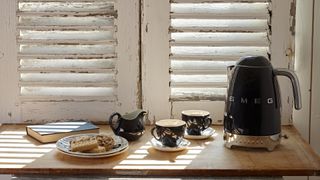 Kitchen with white shutters and wooden countertops showing tea mugs next to a kettle to answer how oftens should you descale your kettle