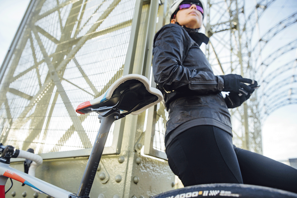 Female cyclist standing next to her women's road bike