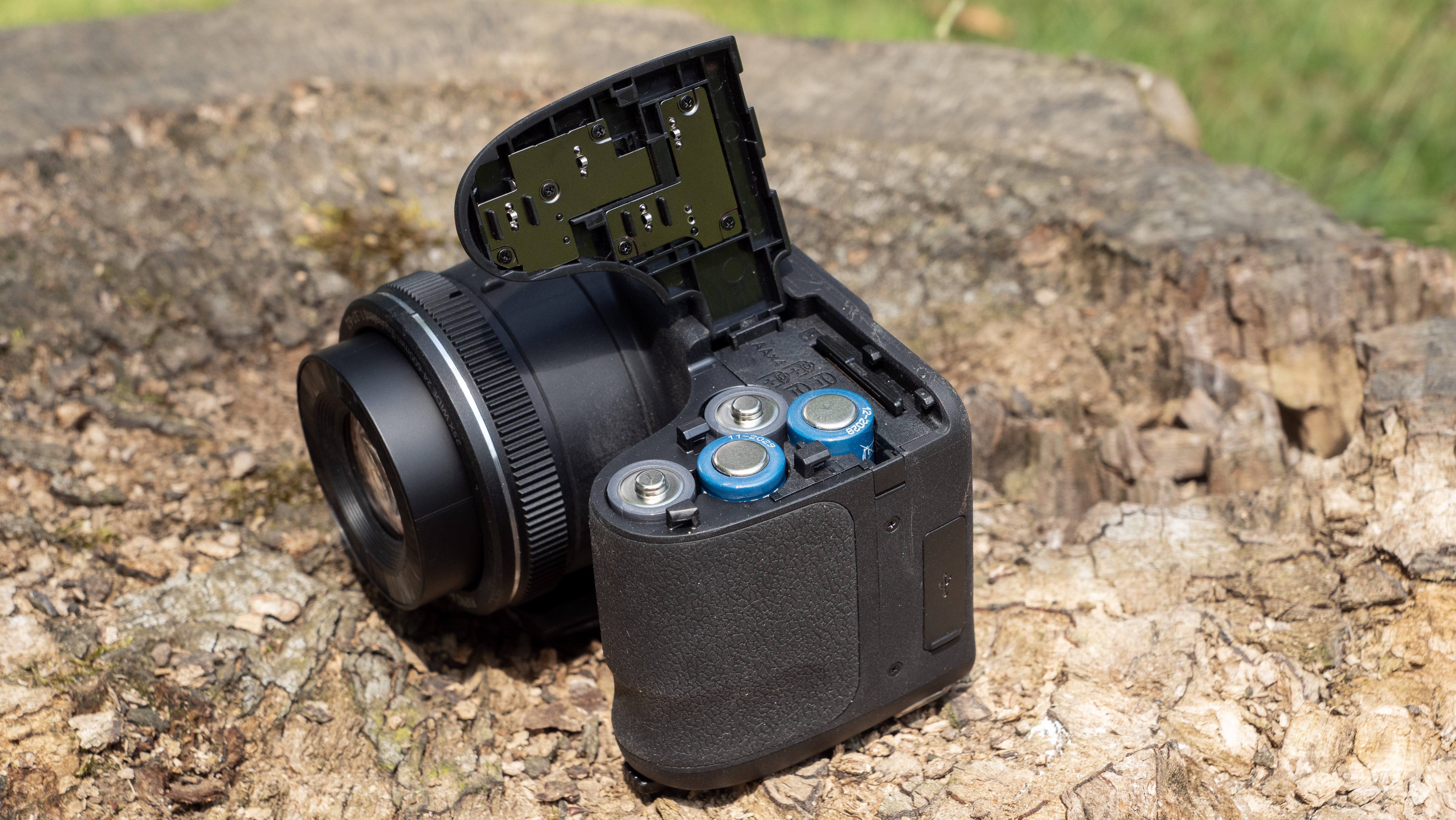 Kodak PixPro AZ255 digital camera in black on a stone surface in front of a green background outside