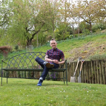 Garden Rescue's Lee Burkhill poses in a verdant green outdoor setting