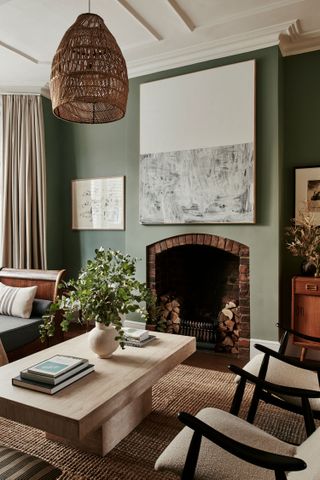 small sage green living room with brick fireplace and pale wooden furniture