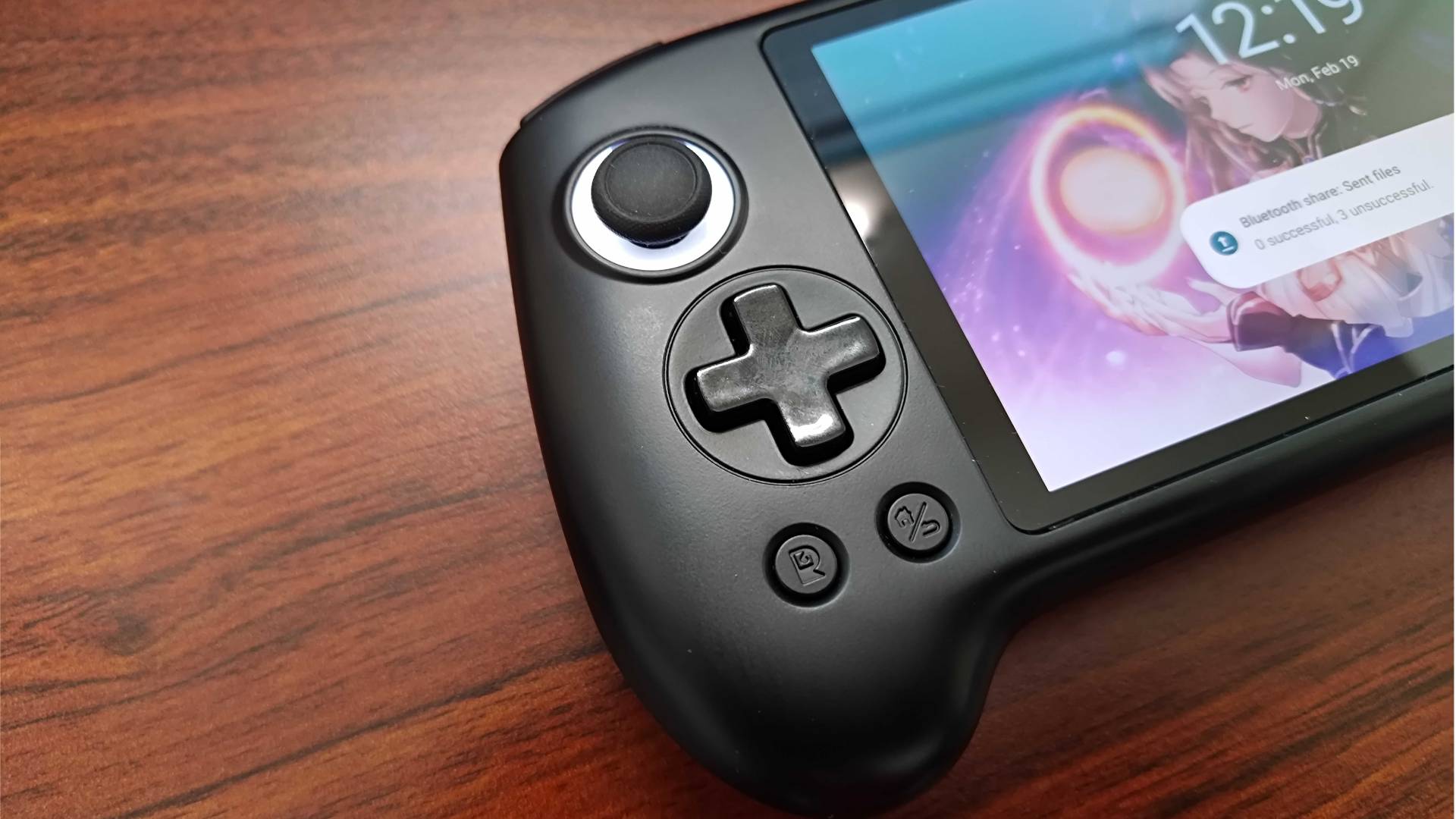 Close up of Anbernic RG556 d-pad with handheld sitting on woodgrain desk.