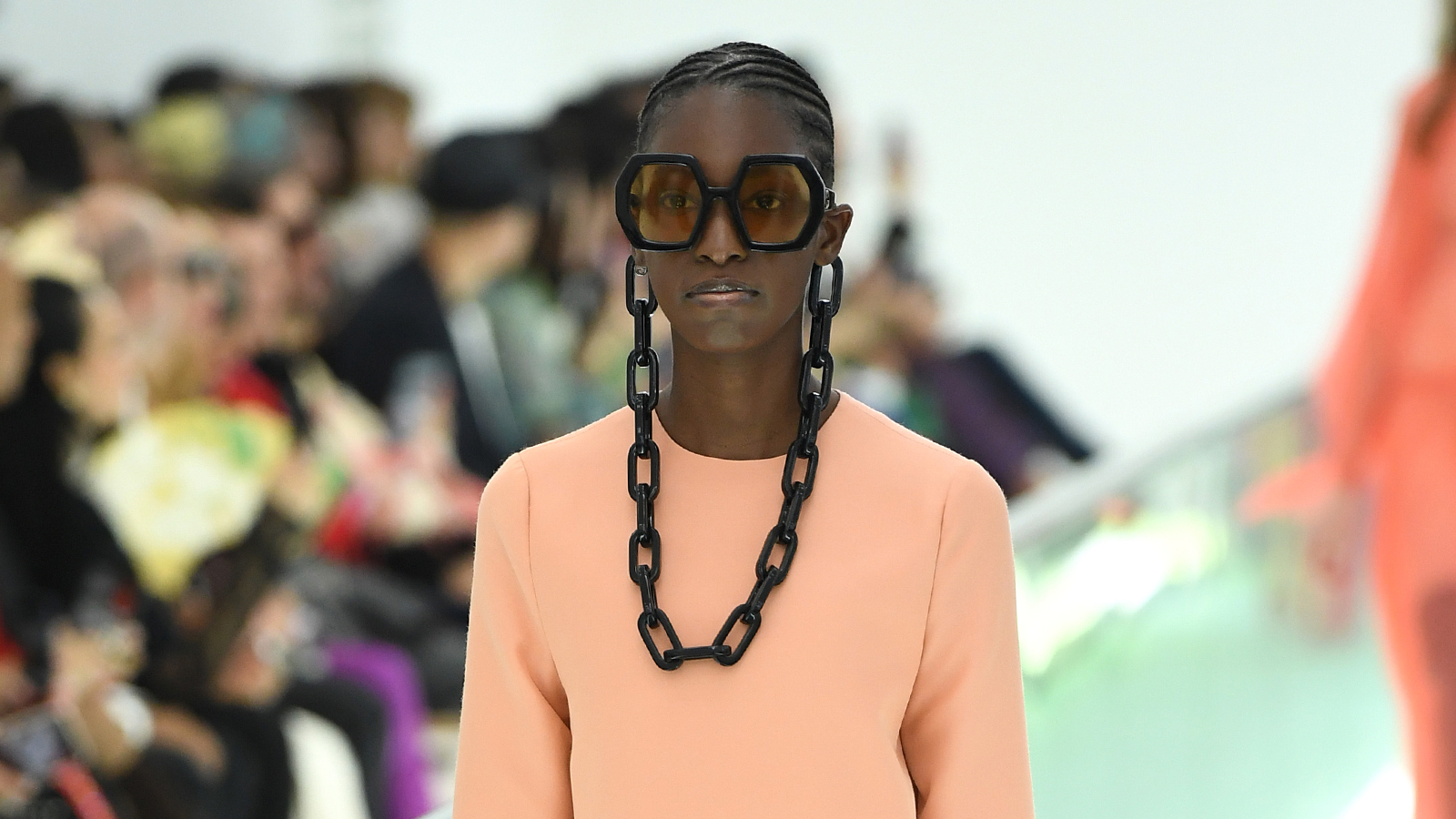 A beautiful model walks the runway for Gucci with her hair set in neat cornrows.