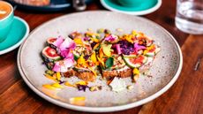 3/4 overhead shot of a brown speckled plate loaded with a toast covered in fig slices and flower petals