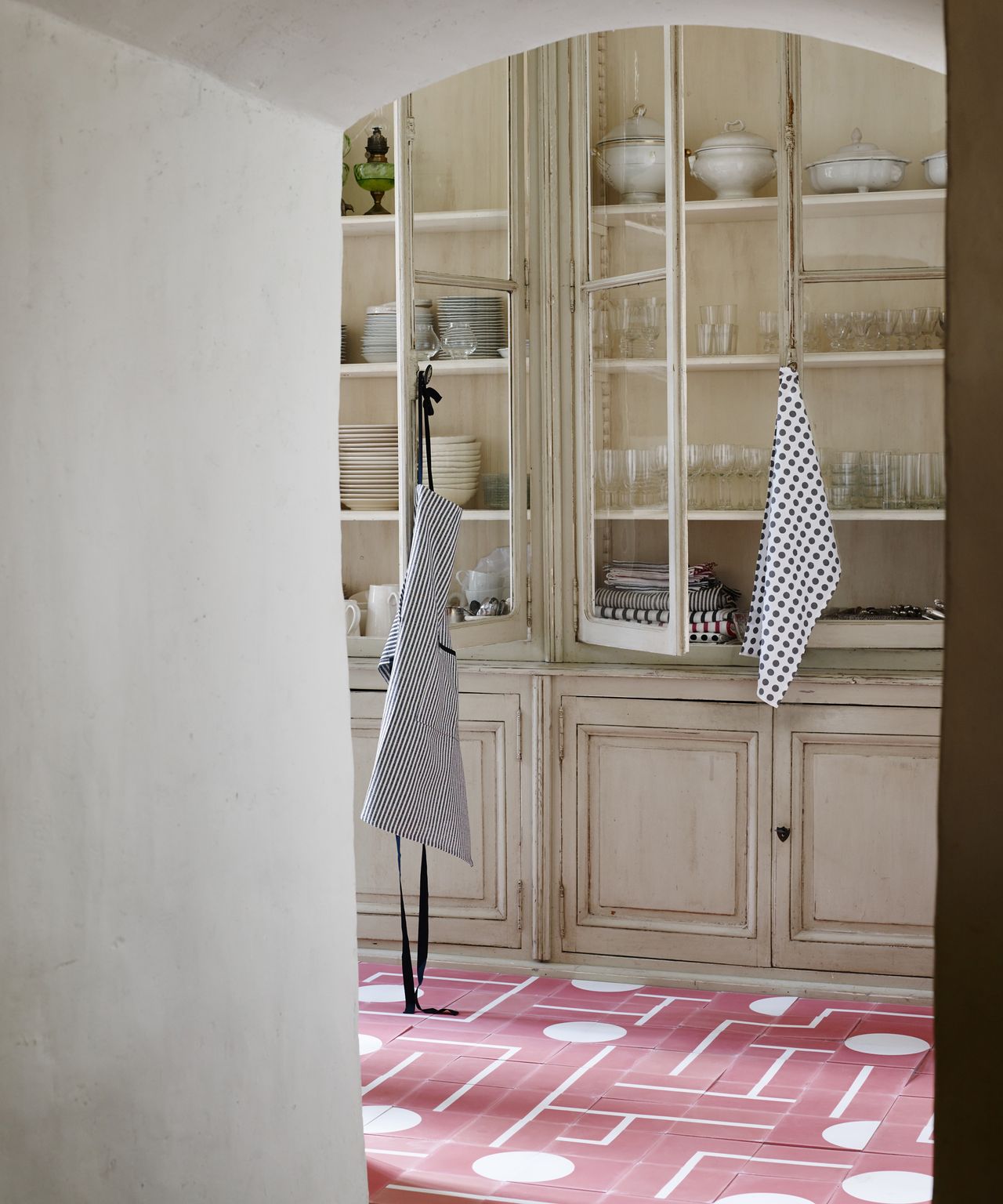 A kitchen with red and white patterned tiles and rustic neutral accessories