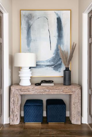 An entryway alcove with a warm stone credenza, warm beige walls, and art on the walls