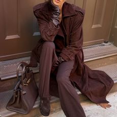 Elsa wears a brown suede jacket, brown leather gloves, brown pants, brown suede ruched loafers, and a brown hermes bag.