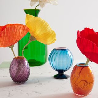 Four colorful glass vases with faux flowers