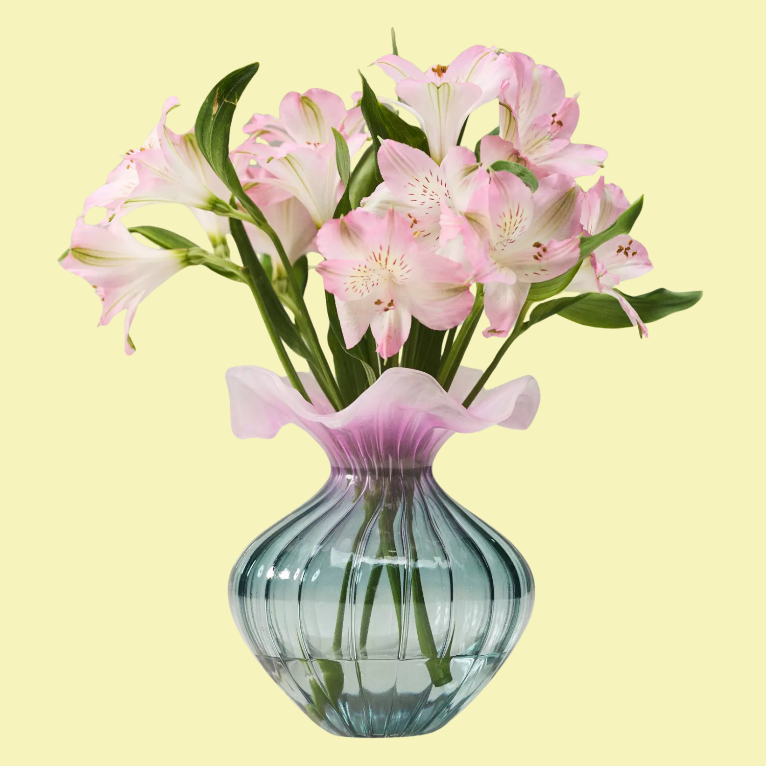 A purple-y pink and blue ruffled glass vase with flowers