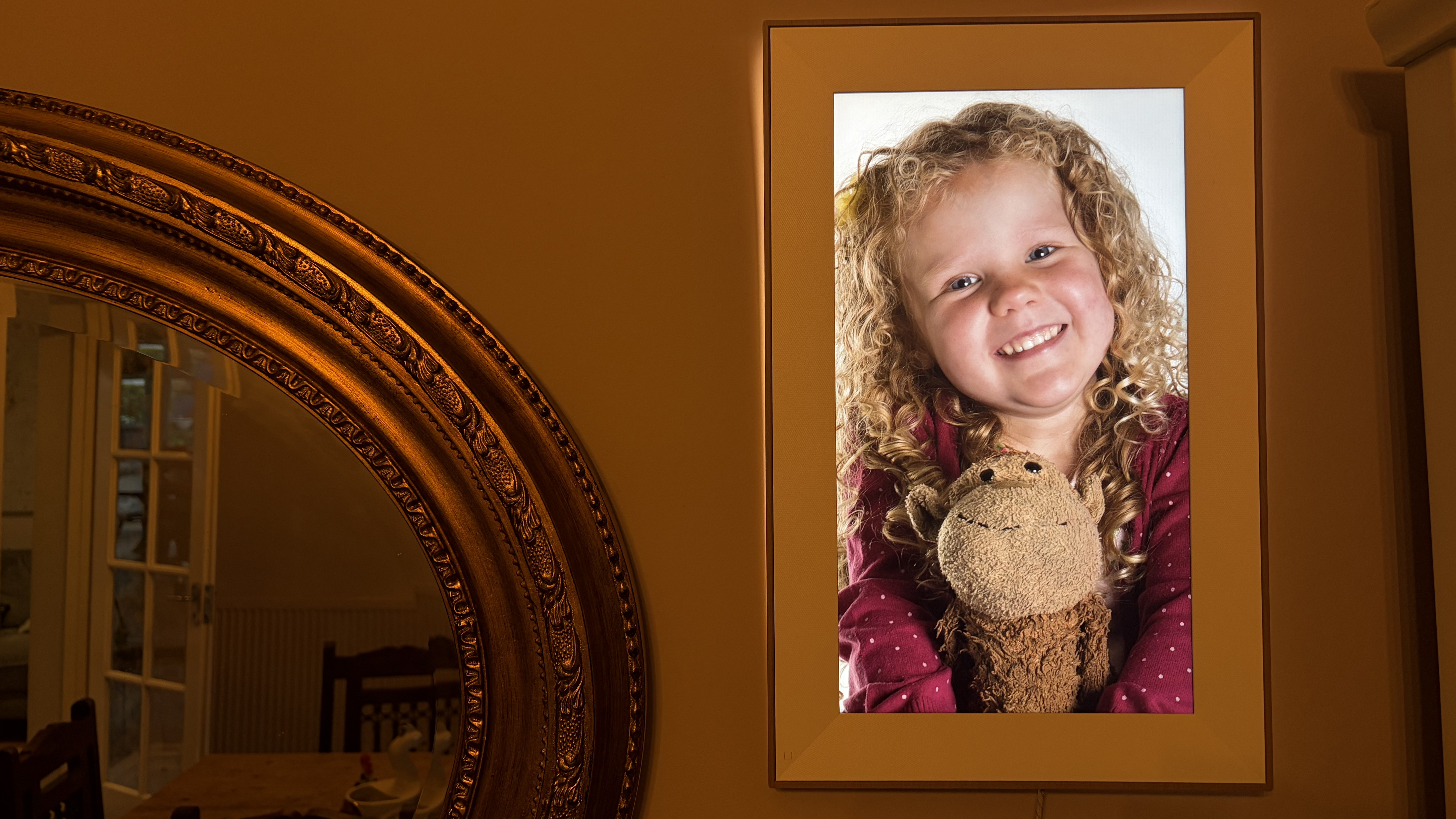 Pexar Starlight digital photo frame in portrait orientation hung on a wall