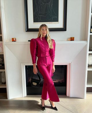 Sofia Richie Grainge wearing a fuchsia, puff-sleeve jacket, and matching pants with black Saint Laurent heels.