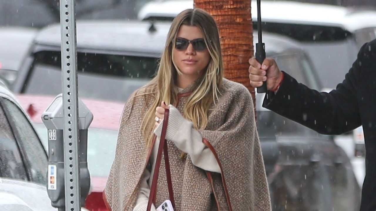 Sofia Richie wearing a tan cape in the rain