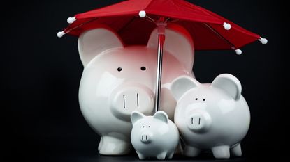 A three-member piggy bank "family" under a red umbrella.