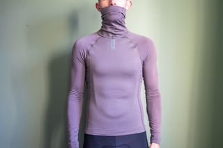 A man wearing a grey Rapha winter base layer with lock neck over his mouth