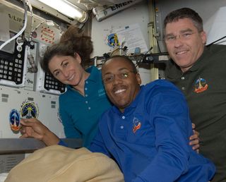 Space shuttle Discovery astronauts Alvin Drew, center, Nicole Stott and Steve Bowen add their mission patch as designed by the late, famed space artist Robert McCall to the International Space Station's wall. 