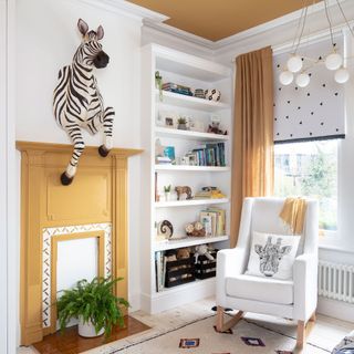 White and yellow nursery with yellow painted fireplace and zebra head mounted above
