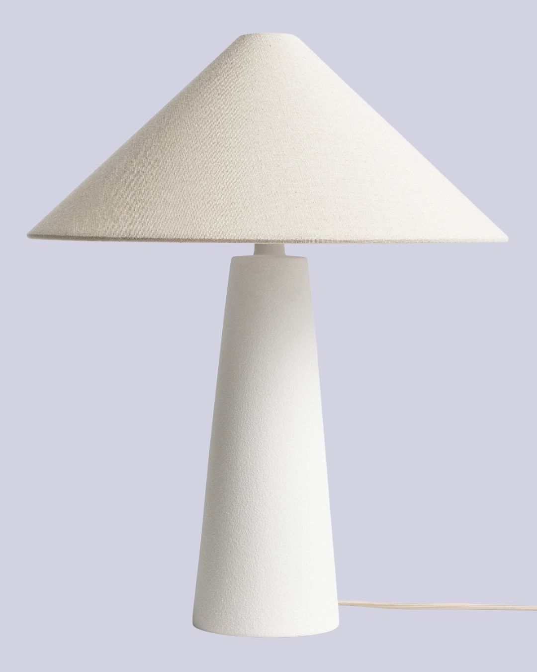 Habitat Conical 49cm Ceramic Table Lamp in White &amp;amp; Cream against lilac background.