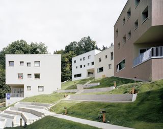 White cube shaped student residence buildings on a hill.