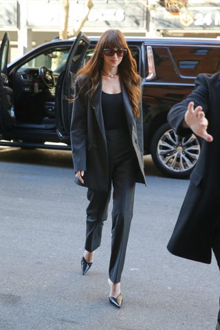 Dakota Johnson in pinstripe trousers and black pointed-toe heels