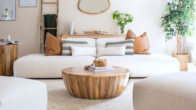 A modern round wooden coffee table in a contemporary living room with white sofa 