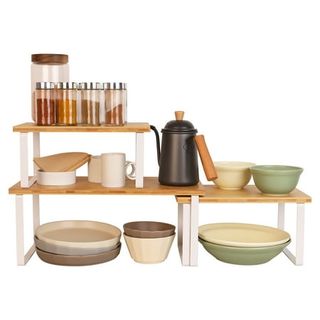 Bamboo shelf risers with white metal legs. Plates and bowls underneath them, spices on top. 