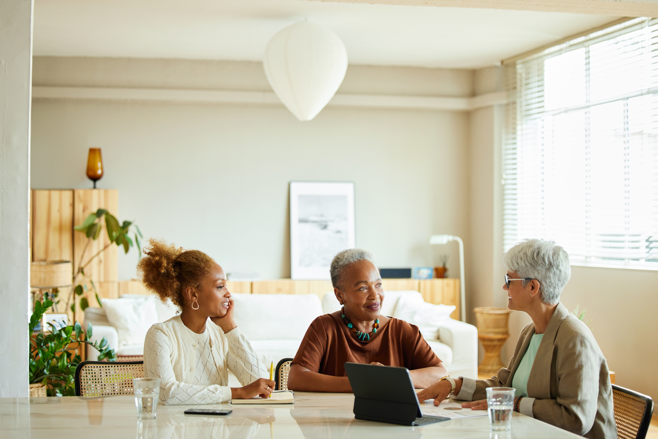 A financial adviser sits with a mother and daughter at dining table to discuss life insurance.