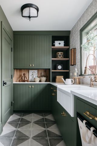 A green kitchen with olive green kitchen cabinets, checked floor tiles and a butler sink