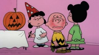 Lucy studies an angry Charlie Brown's head at a Halloween party in It's The Great Pumpkin, Charlie Brown.