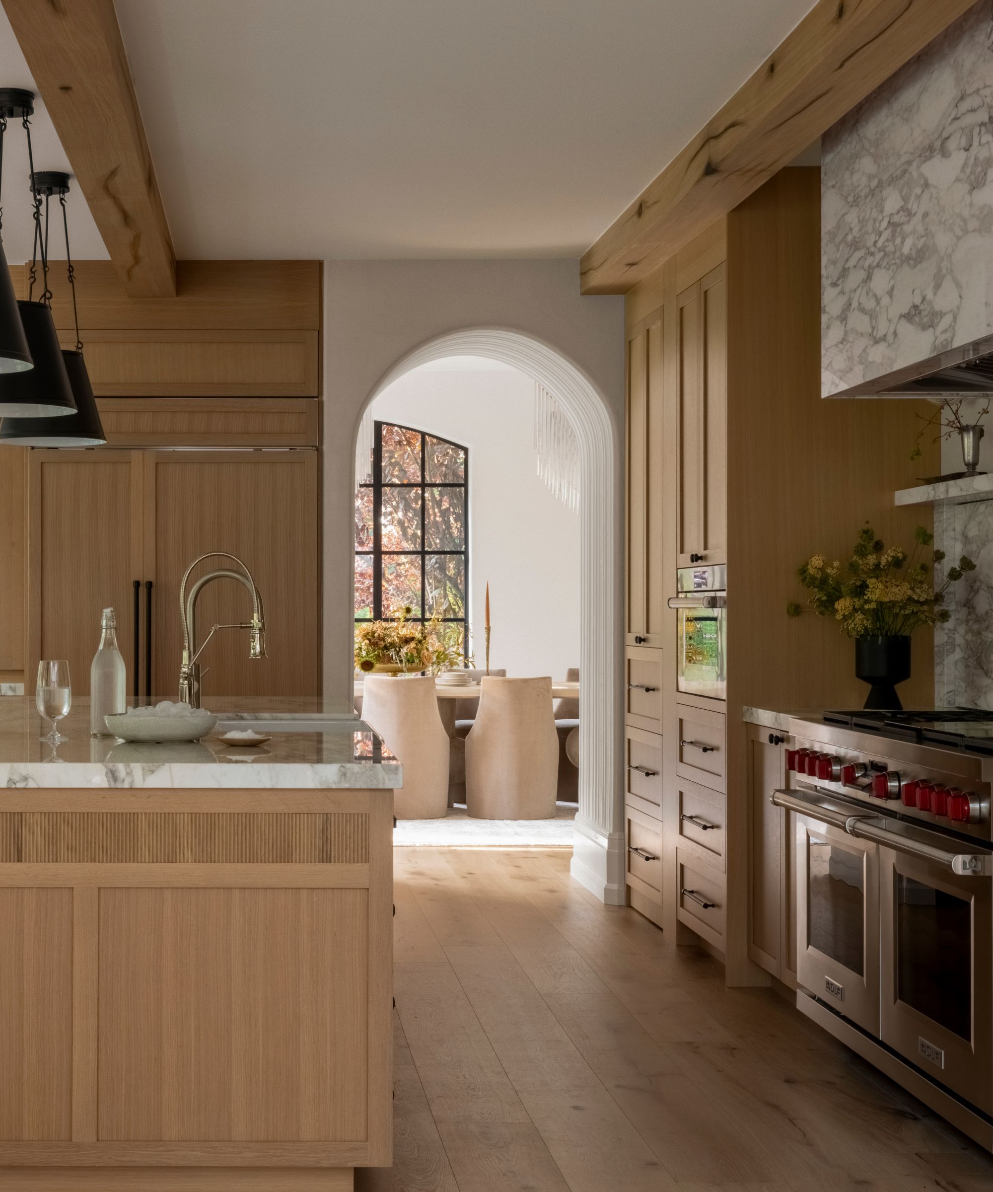 A wooden kitchen with a textured archway into the dining room