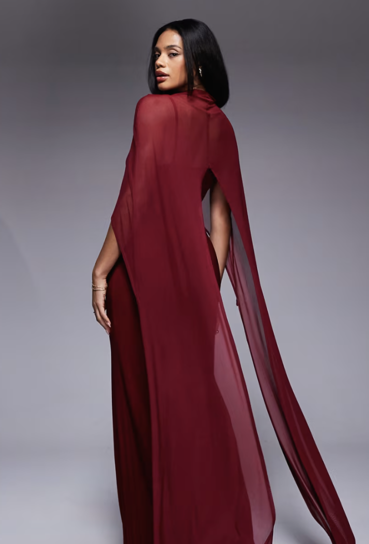 A model wearing a maroon cape dress