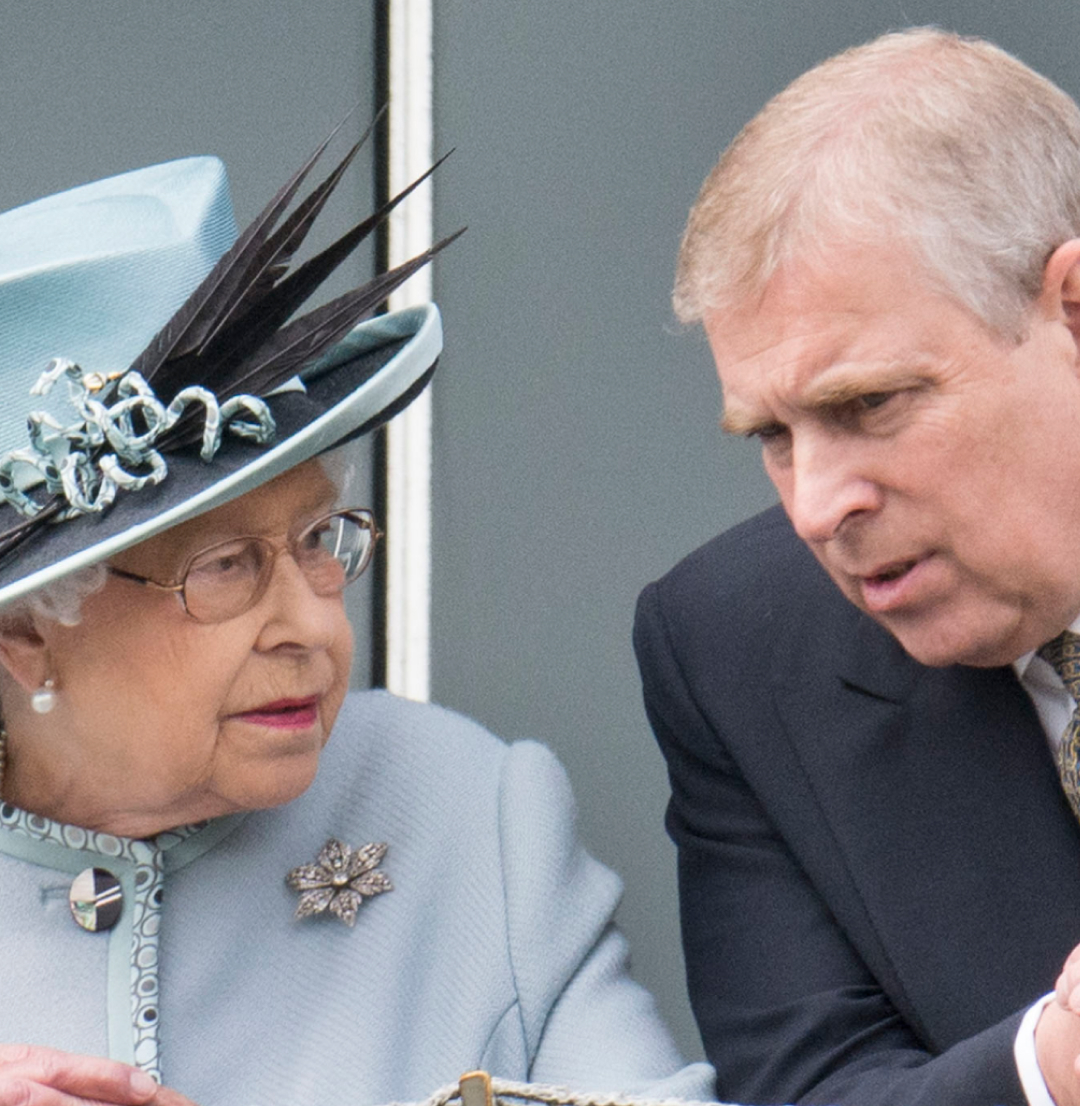 Queen Elizabeth in a blue coat and hat leaning forward and talking to Andrew Mountbatten-Windsor at the Epsom Derby