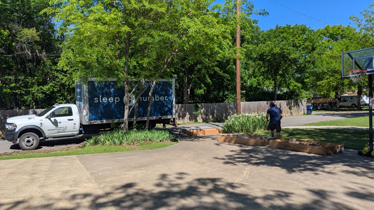Sleep Number lorry pulling up at driveway with trees and blue skies