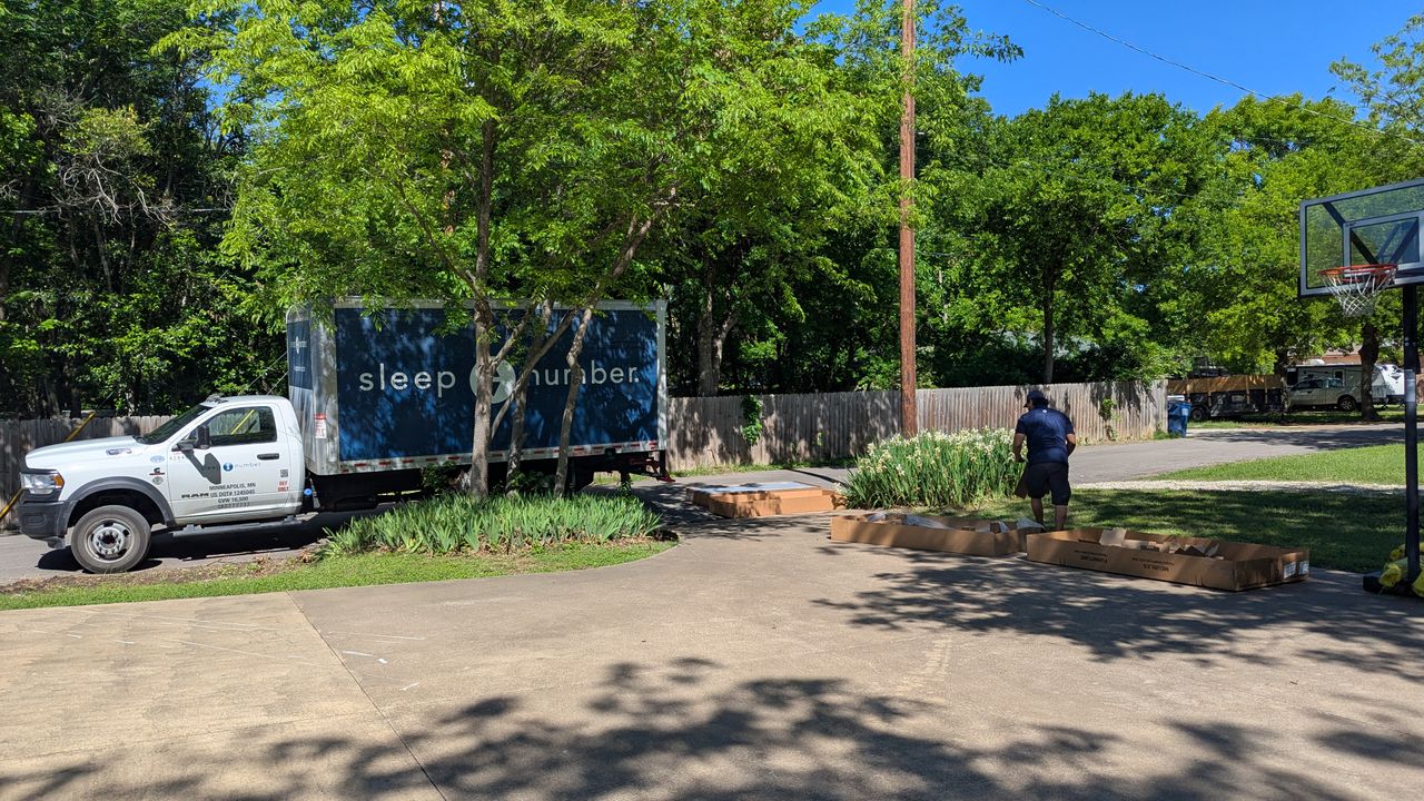 Sleep Number lorry pulling up at driveway with trees and blue skies