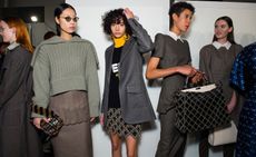 Models wear a range of dark knitwear and plaid blazers, with short and long skirts