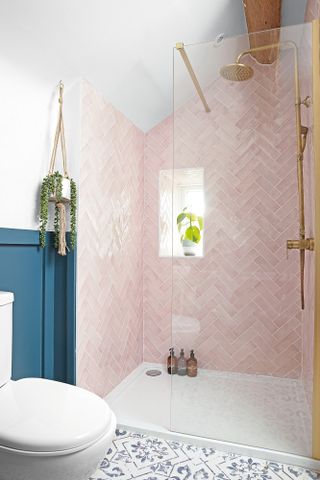 Walk-in shower with glass screen and pink herringbone wall tiles