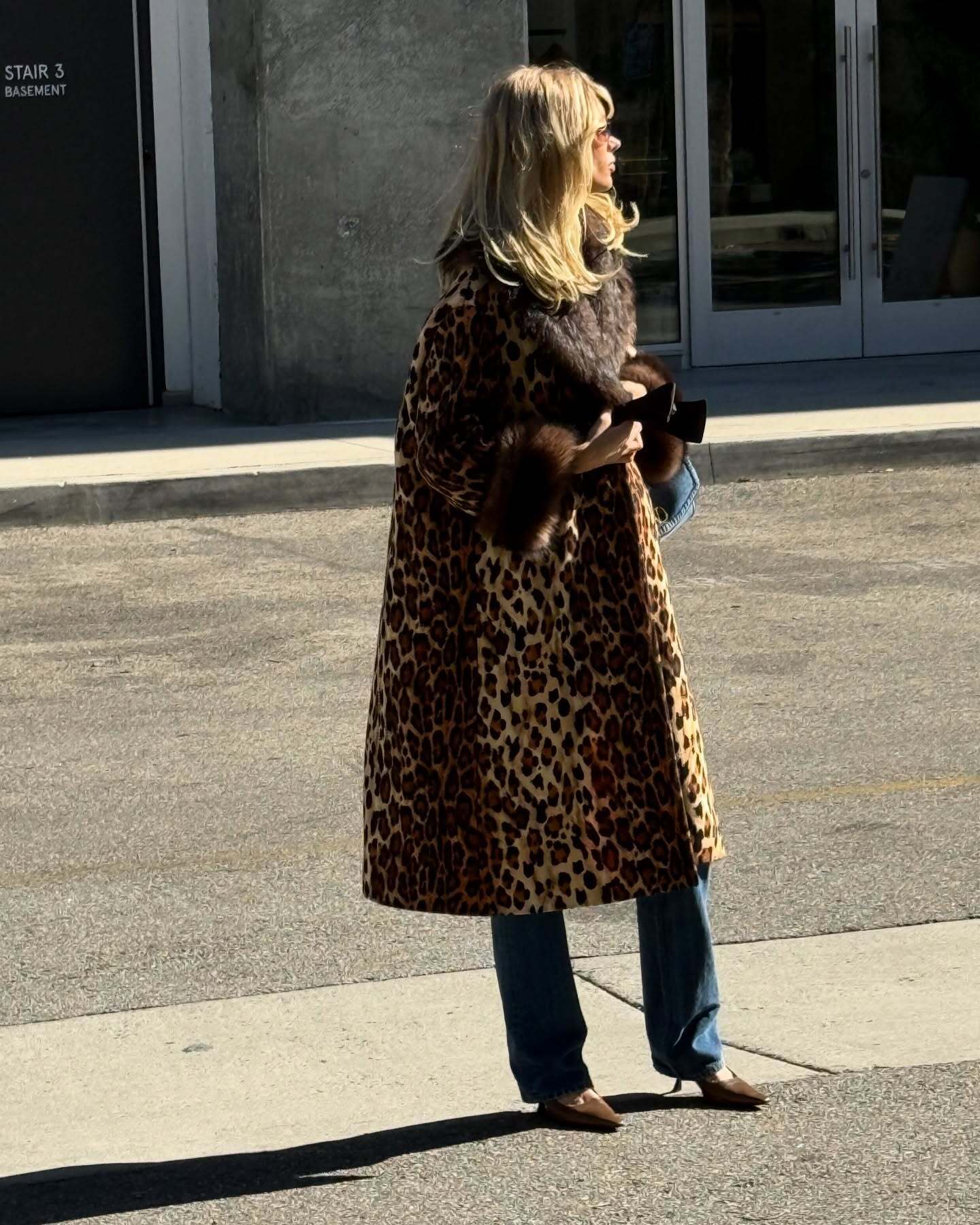Elsa Hosk wearing a Disney T-shirt, Valentino leopard-print coat, bootcut jeans, and brown kitten heels from The Row.