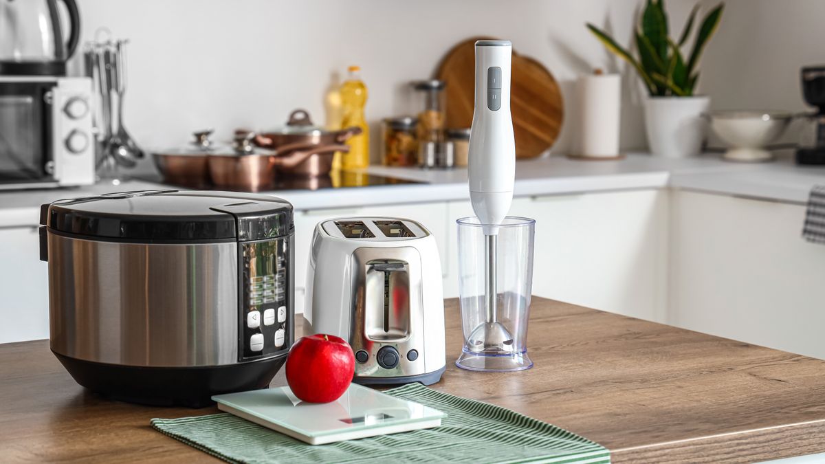 Blender, toaster, multi cooker and apple on wooden table in kitchen