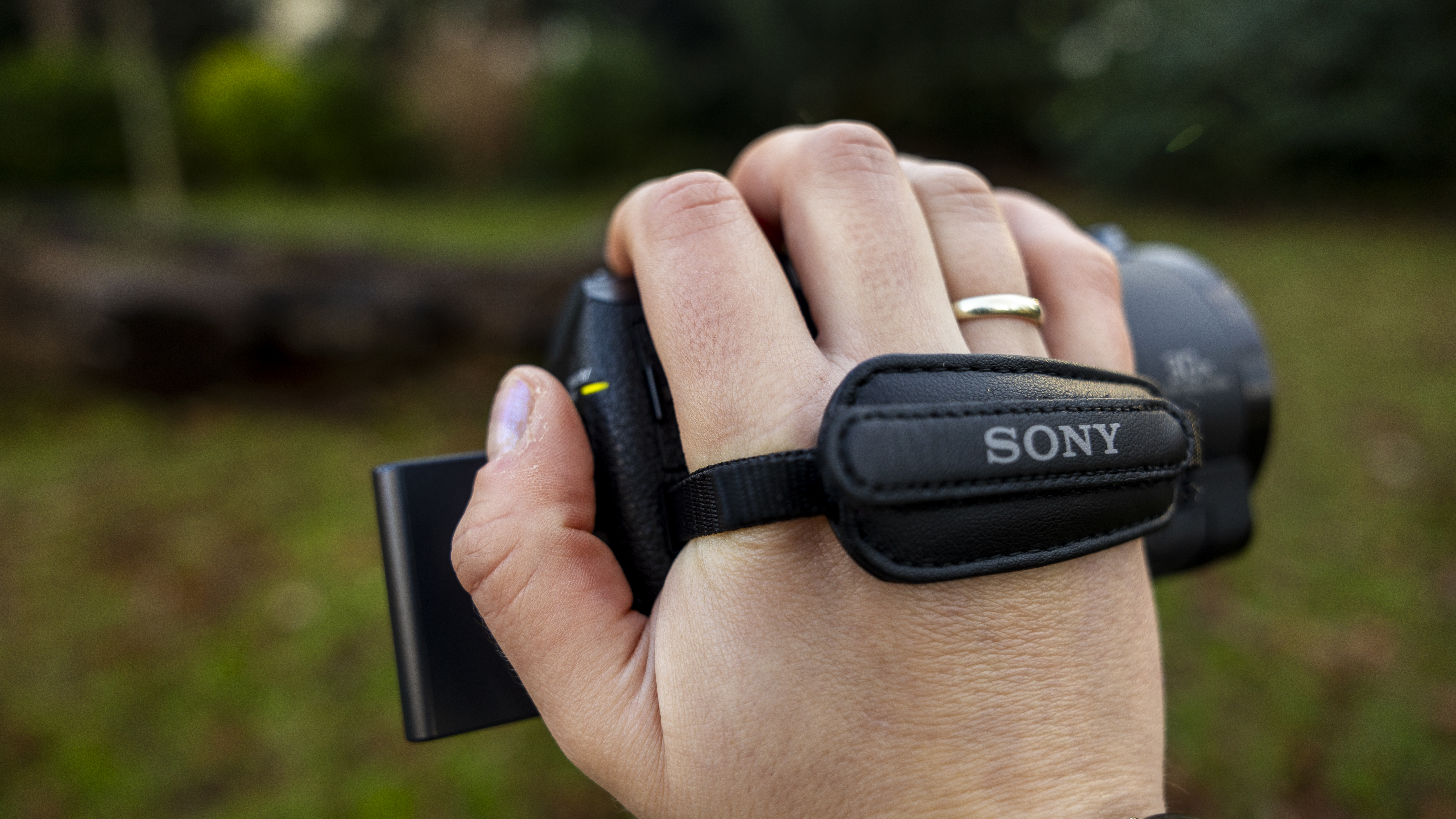 A photographer holding the Sony AX43 by the wrist strap