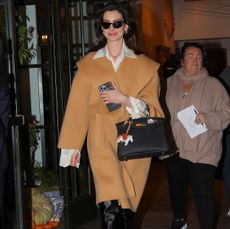 Anne Hathaway in a camel wool wrap coat and knee-high boots