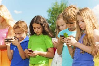 Group of kids on a summer day looking at their cell phones