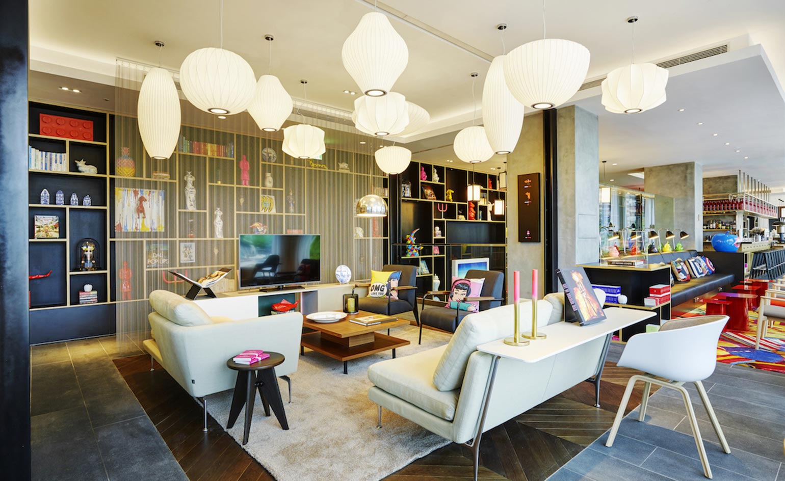 CitizenM North Gate lounge with white sofas, different shaped hanging lantern lights, inset brown herringbone wooden floor surrounded by grey floor tiles