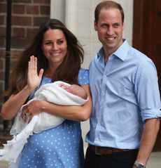 Princess Kate and Prince William standing outside the hospital holding Prince George wrapped in a white blanket