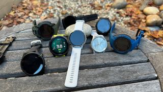 A bunch of Garmin watches sitting on a table: The Venu 3, Forerunner 965, 955, 265, and 255 Music, Instinct 2 Solar and 2X Solar, and Vivomove Trend.