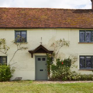 exterior of cottage with climbing roses rendered walls and red clay roof tiles